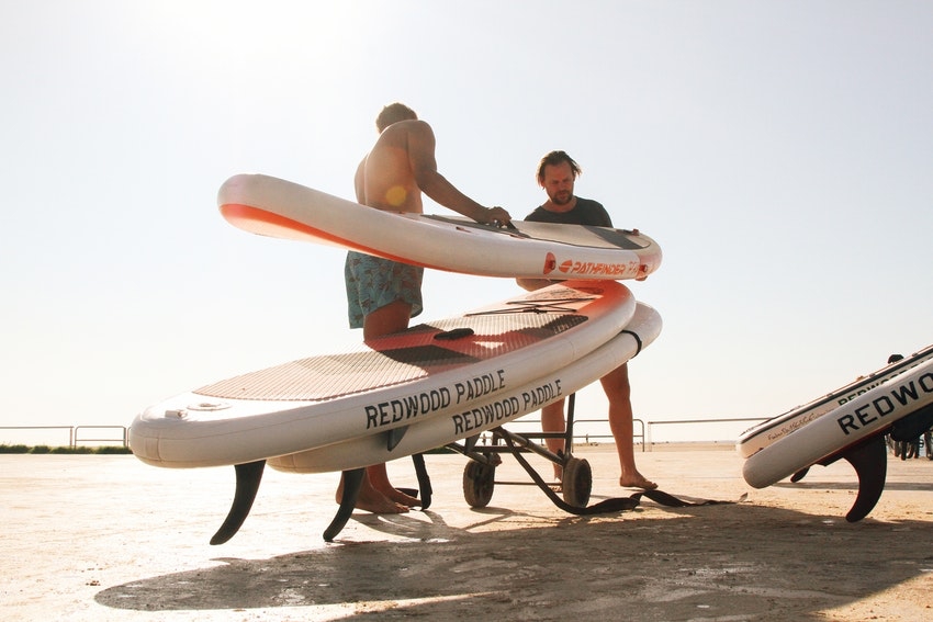 hommes sur la plage avec planche de paddle