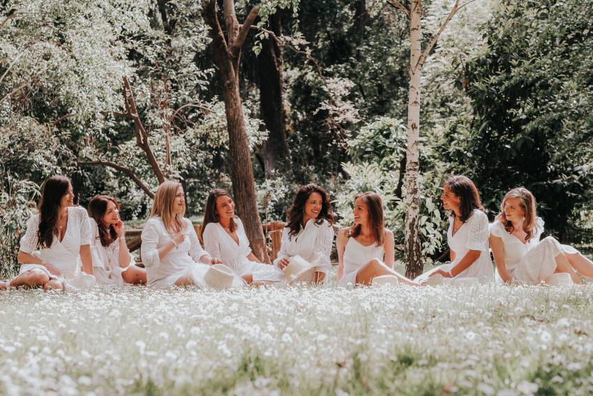 groupe de copines en robes blanches assises dans un jardin