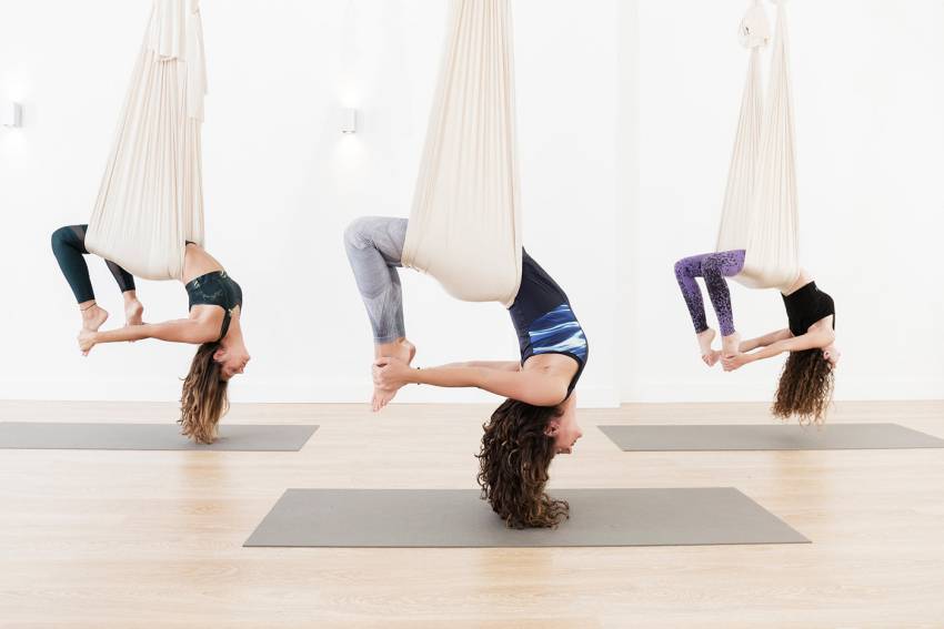 trois femmes qui font du yoga aerien