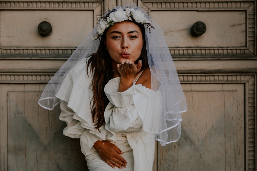 future mariee avec couronnes de fleurs blanches et voile qui envoi un bisou